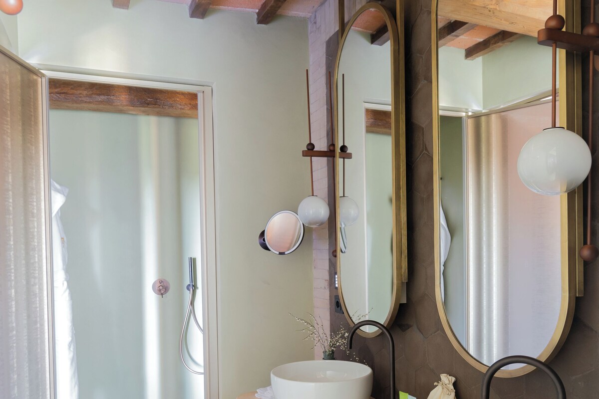 A bathroom with two sinks, a large mirror, and a shower.