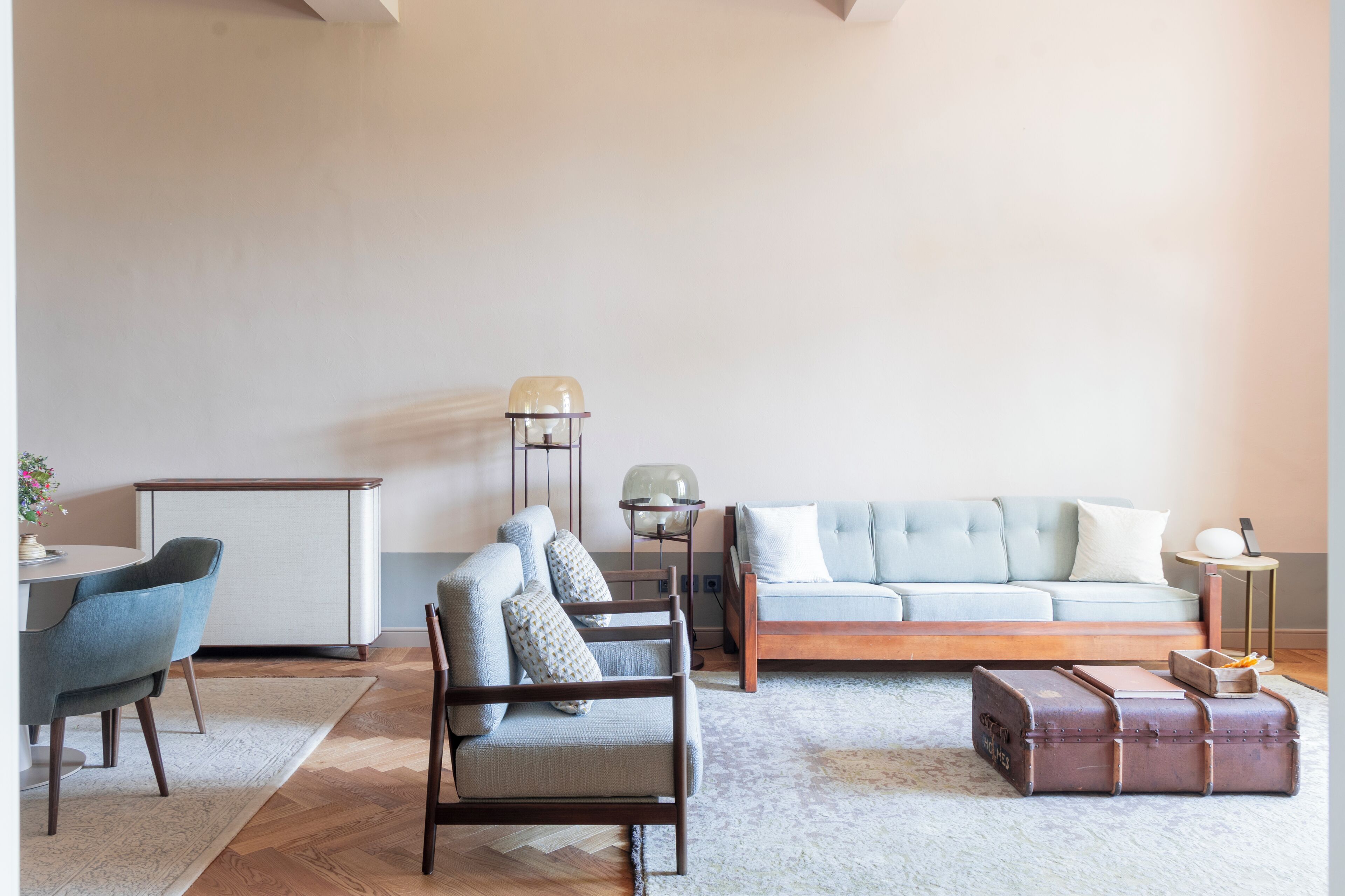 Een moderne woonkamer met een bank, stoelen, een tafel en een lamp.