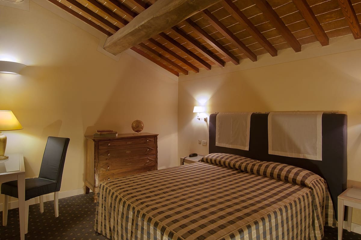 A bedroom with a bed, a chair, a dresser, a lamp, and a nightstand.