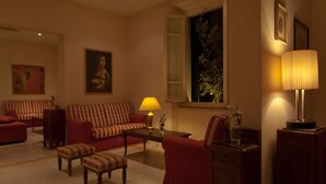 Uma sala de estar com sofá, poltronas, mesa de centro e abajur.