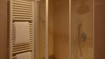Ein modernes Badezimmer mit einer gläsernen Duschkabine, einem weißen Handtuchhalter und einer Badewanne.