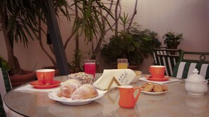 Mesa posta para o café da manhã com croissants, doces e um bule de chá.