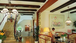 A spacious living room with a staircase, a chandelier, and a painting on the wall. - Boutique-Hotel Das Haus am Walde (Bad Bevensen)