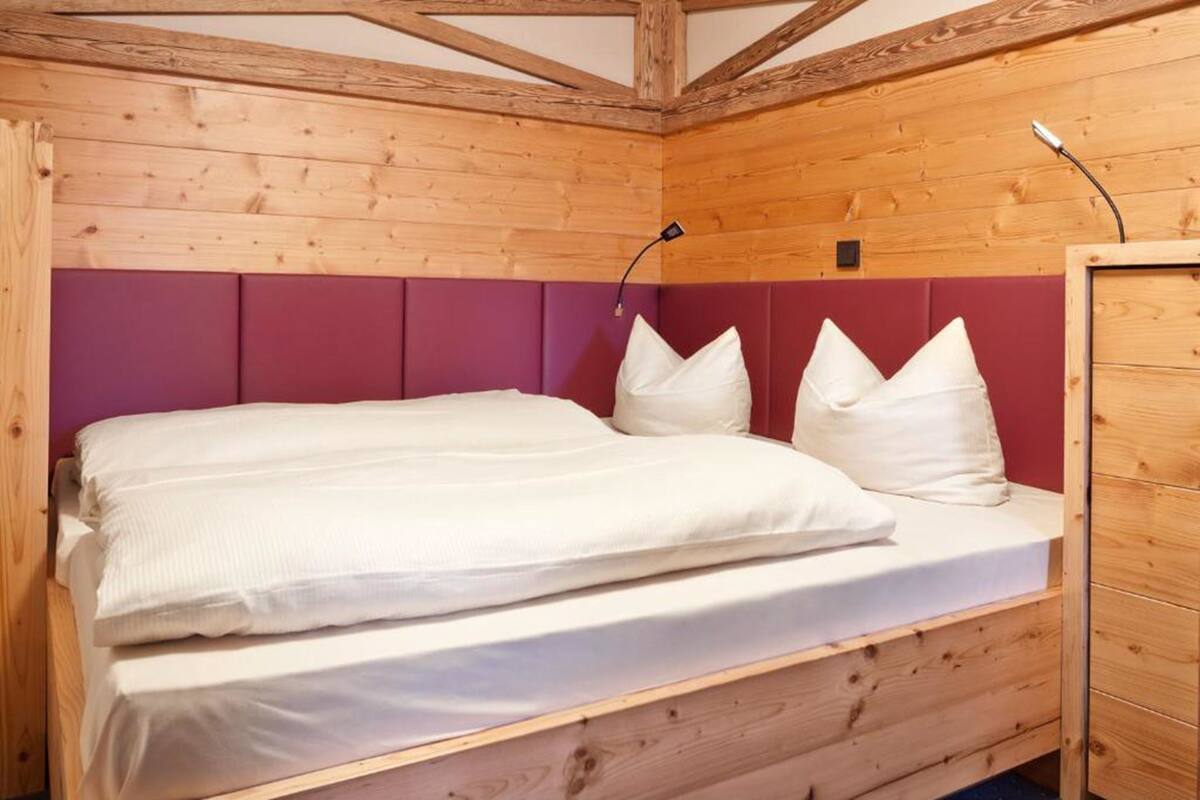 Ein Holzhütten-Zimmer mit einem Bett, einer roten gepolsterten Kopfteil und einem Holzschrank.
