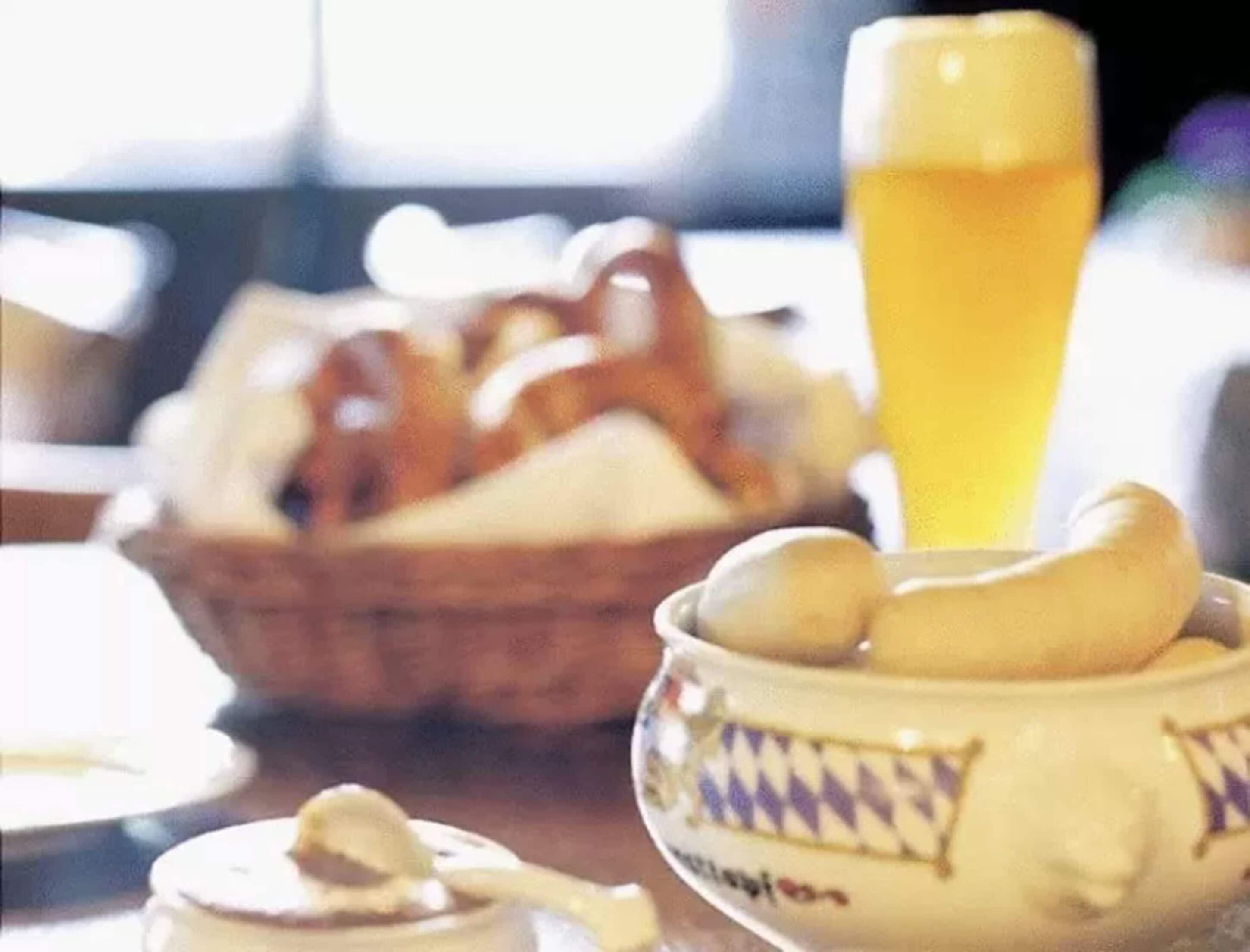 Una mesa con una cesta de pretzels, un plato de plátanos y una jarra de cerveza.