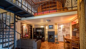 A spacious living area with a wooden floor, a fireplace, a dining table, and a staircase with a wrought iron railing. - Hotel Casona Solar (Arequipa)