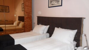 A hotel room with two single beds, a large mirror, a framed picture on the wall, and a bedside lamp. - B&B La Nara (Turin)