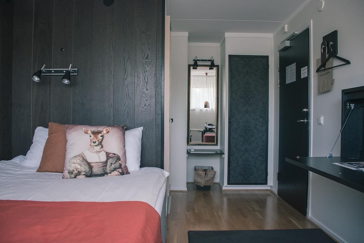 Un dormitorio con cama, cómoda, espejo y escritorio.