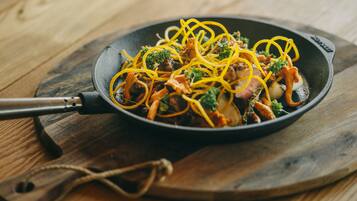 A skillet with a stir-fry dish on a wooden board.