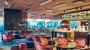 Ein stilvoller Lounge-Bereich mit bequemen Sitzmöglichkeiten, einer Bar mit einer Auswahl an Flaschen und großen Fenstern mit Ausblick.