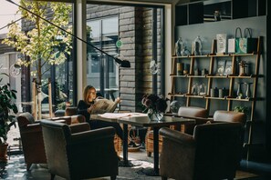 Un espace intérieur accueillant avec des fauteuils en cuir, une table et une bibliothèque agrémentée d’objets décoratifs.