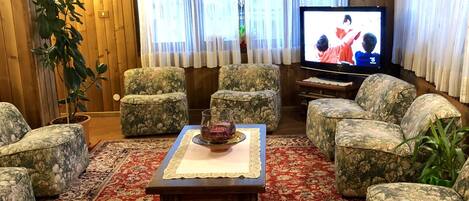 A living room with floral-patterned sofas, a wooden coffee table, and a television.