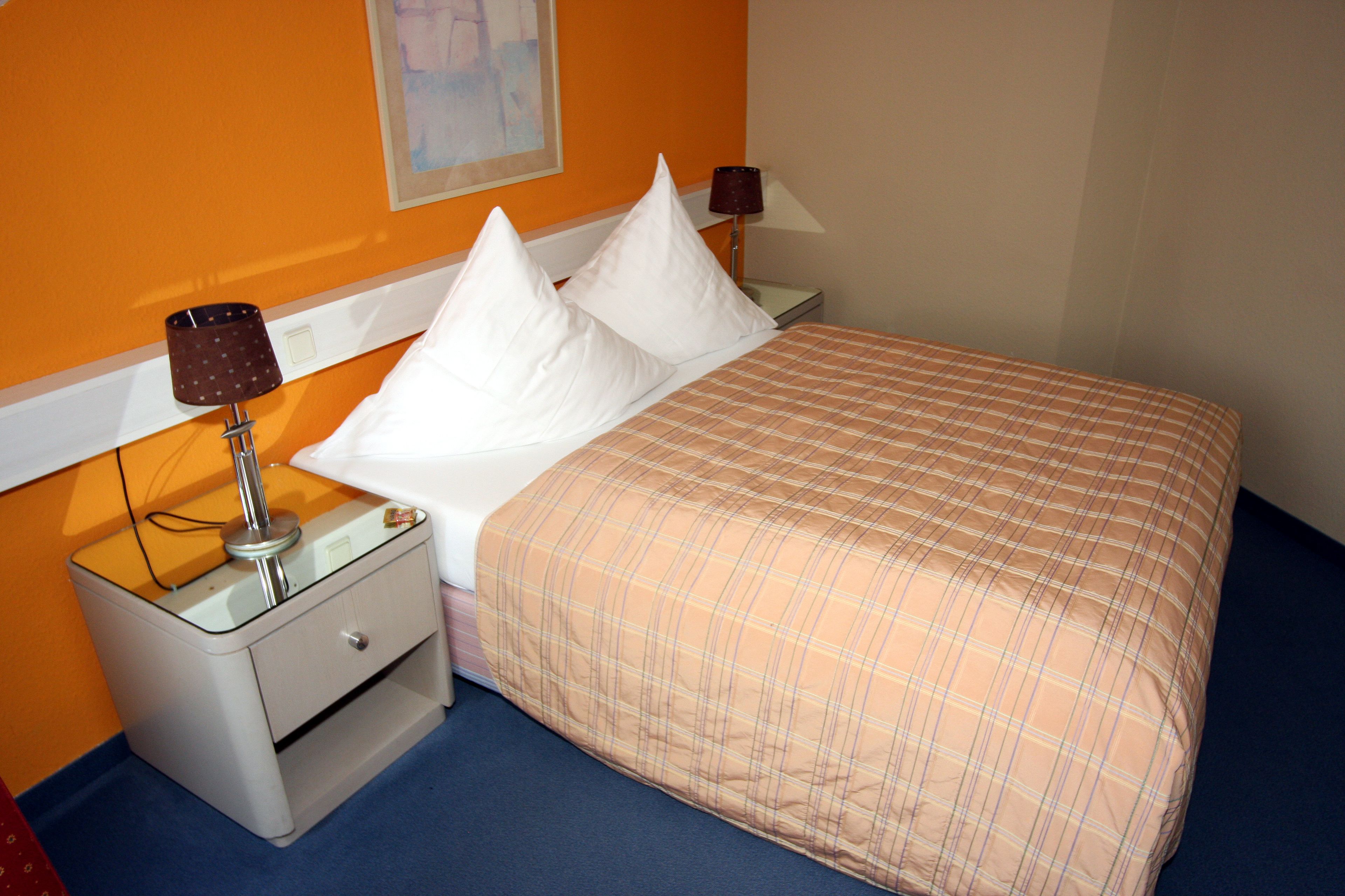 Une chambre d’hôtel avec un lit, deux tables de chevet et deux lampes.