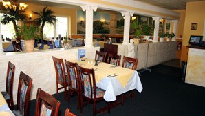 A restaurant with a long counter, wooden chairs with colorful cushions, and a white tablecloth-covered table. - Hotel Ilmenauer Hof (Ilmenau)