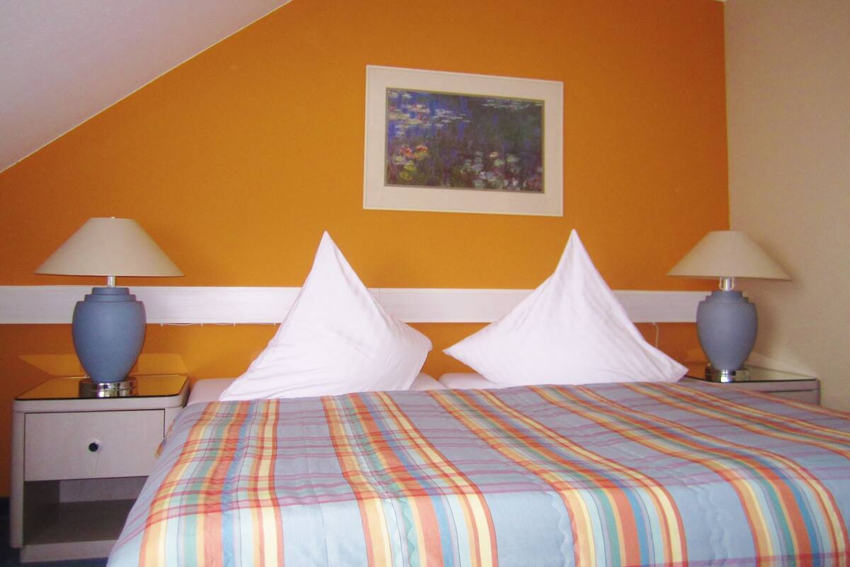 A hotel room with a bed, two nightstands, two lamps, and a painting on the wall.
