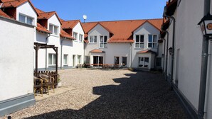 A courtyard with white buildings, red roofs, and a gravel ground. - Hotel Ilmenauer Hof (Ilmenau)