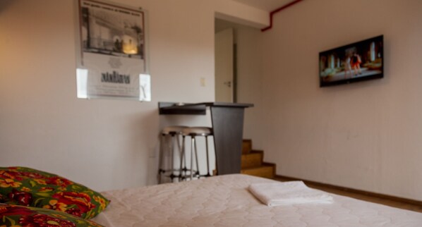 A bedroom with a bed, a desk, and a chair. There is a poster on the wall and a painting above the desk. - Eco Hotel Oceanomare (Florianópolis)