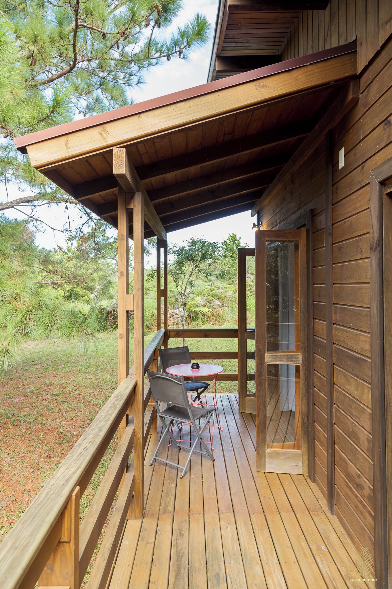 A wooden deck with a table and chairs, surrounded by a wooden railing.