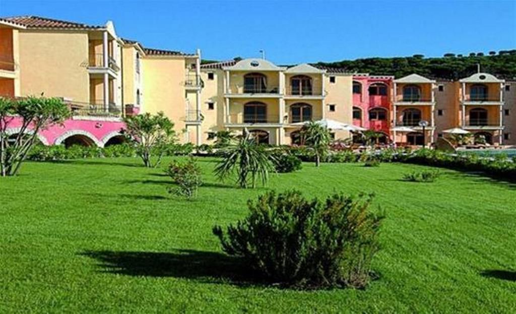 A hotel with multiple buildings, a well-maintained lawn, and a clear sky.