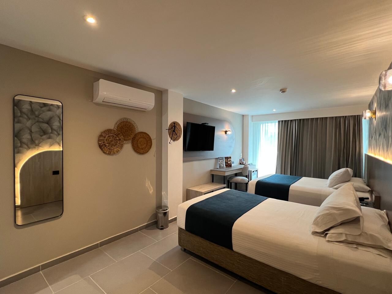 Une chambre d’hôtel avec deux lits, un bureau, une télévision et un appareil de climatisation.