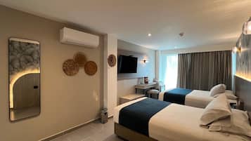 Une chambre d’hôtel avec deux lits, un bureau, une télévision et un appareil de climatisation.