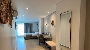 A modern hotel room with a large bed, a desk, a chair, a mirror, and a decorative wall piece. - ZiOne Luxury Hotel Pereira (Pereira)