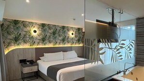 A modern bedroom with a bed, bedside table, and a large mirror. - ZiOne Luxury Hotel Pereira (Pereira)