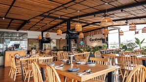 A spacious restaurant with wooden tables and chairs, a bamboo ceiling, and hanging pendant lights. - ZiOne Luxury Hotel Pereira (Pereira)