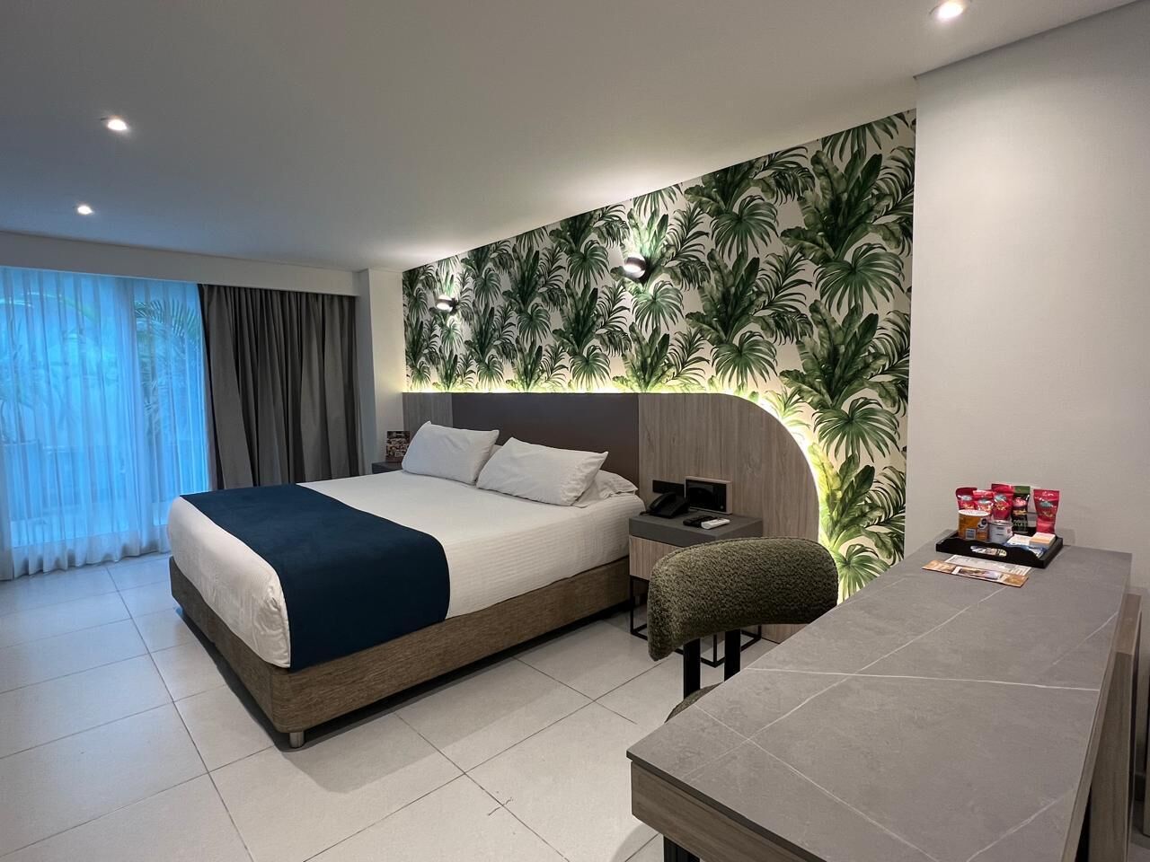 A modern hotel room with a large bed, a desk, and a seating area.
