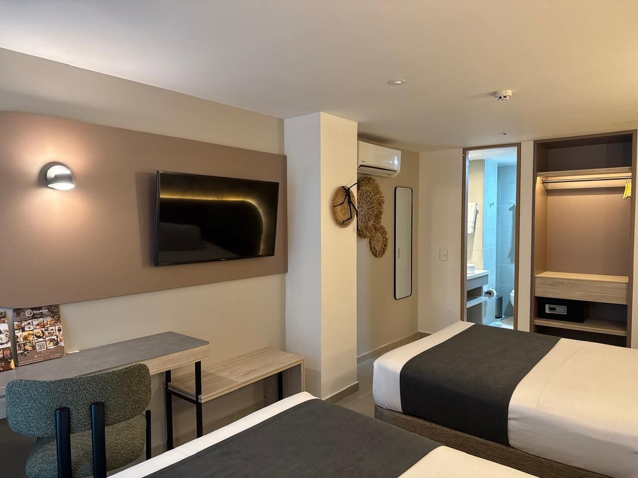 A hotel room with a bed, a desk, a chair, a TV, and a wardrobe.