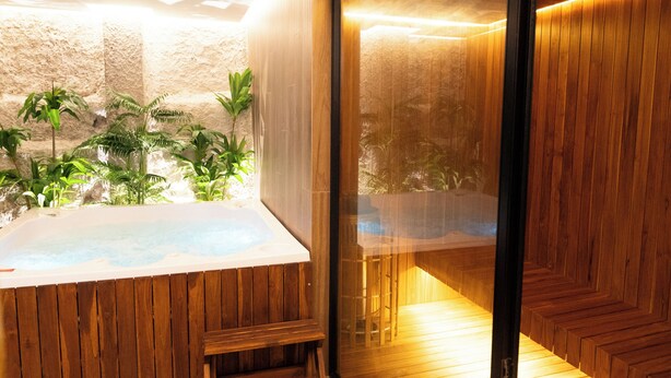 A spa area with a hot tub, wooden flooring, and a view of a landscaped garden. - ZiOne Luxury Hotel Pereira (Pereira)