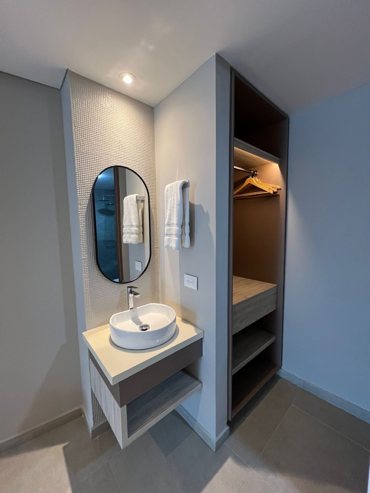 Un baño moderno con un lavabo redondo, un espejo y un perchero para toallas.