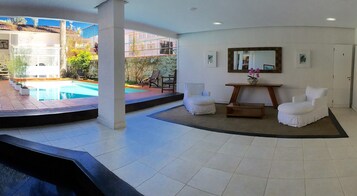 Un espacio interior moderno con piscina, sillas blancas y una mesa de madera.