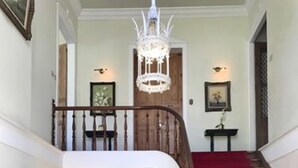 Una imponente escalera con alfombra roja, un candelabro y barandilla de madera.