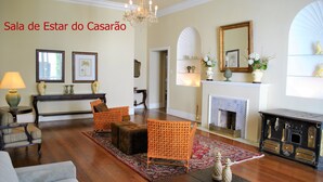 Una sala de estar con chimenea, cuadros enmarcados y una araña.