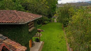 Una casa con tejado de baldosas, un jardín con césped y un sendero de piedra que lleva a una reja.