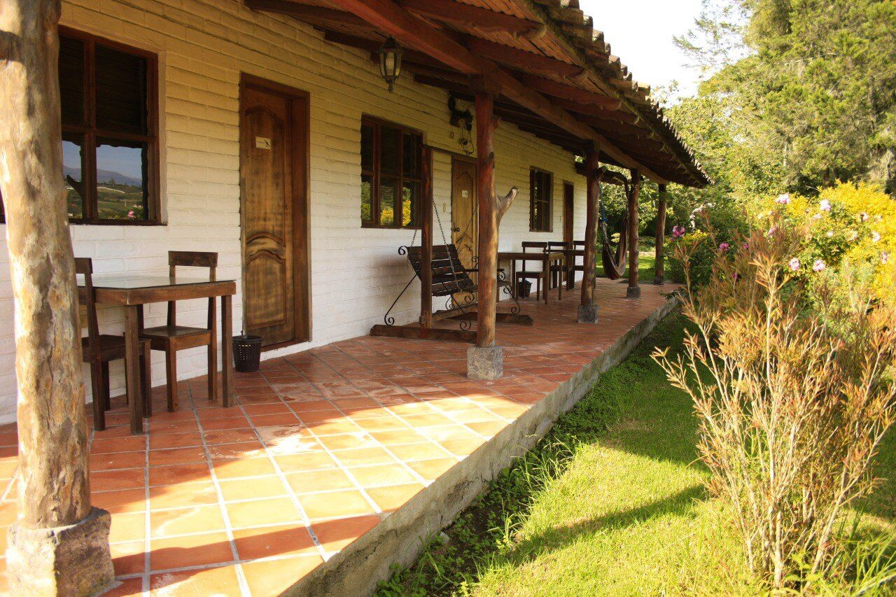 A rustic wooden house with a porch, a swing, and a dining table.