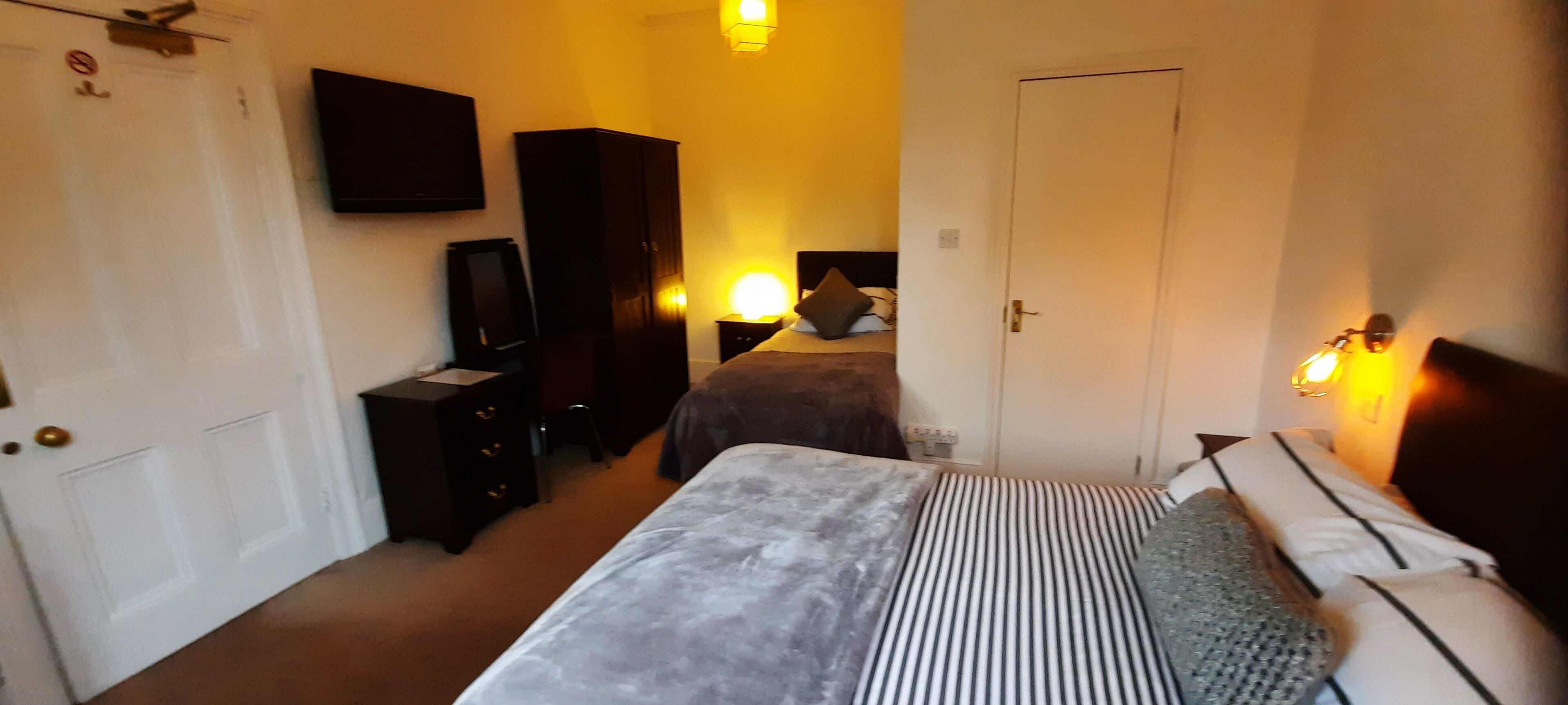 Un dormitorio con cama, cómoda, televisor y armario.