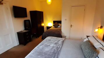 Un dormitorio con cama, cómoda, televisor y armario.