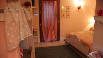 A bedroom with a bed, a bedside table, a dresser, a mirror, a door with curtains, and wall-mounted lights.