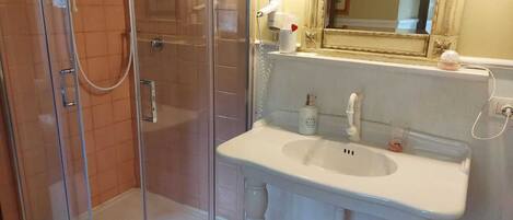 A bathroom with a glass-enclosed shower, a white sink, and a mirror above the sink.