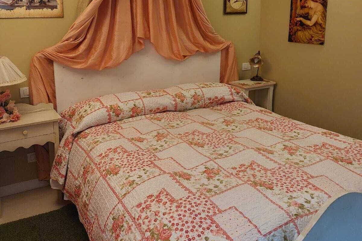 A bedroom with a bed, a nightstand, a lamp, and wall art.