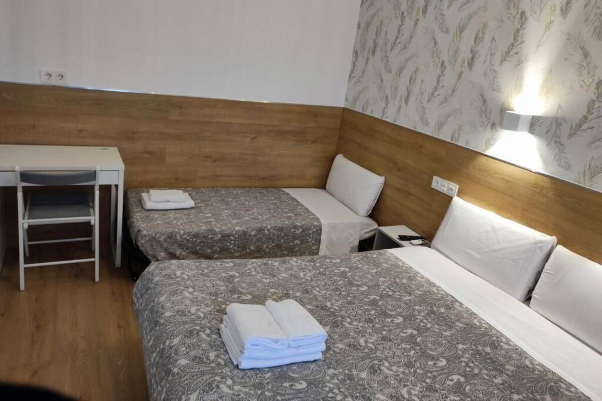 A hotel room with two beds, a desk, and a nightstand.