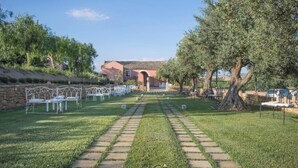 Un lieu de réception pour mariage situé dans un jardin, avec un chemin de pierre menant à un bâtiment doté d’une entrée en arc de cercle.