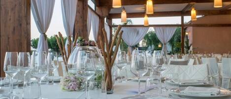 A banquet table set for a formal event with white tablecloths, glassware, and cutlery.