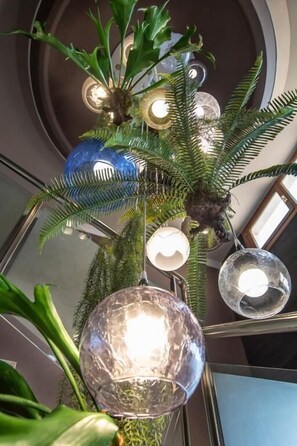 A staircase with a decorative plant arrangement featuring a central tree-like structure with hanging spherical lights.