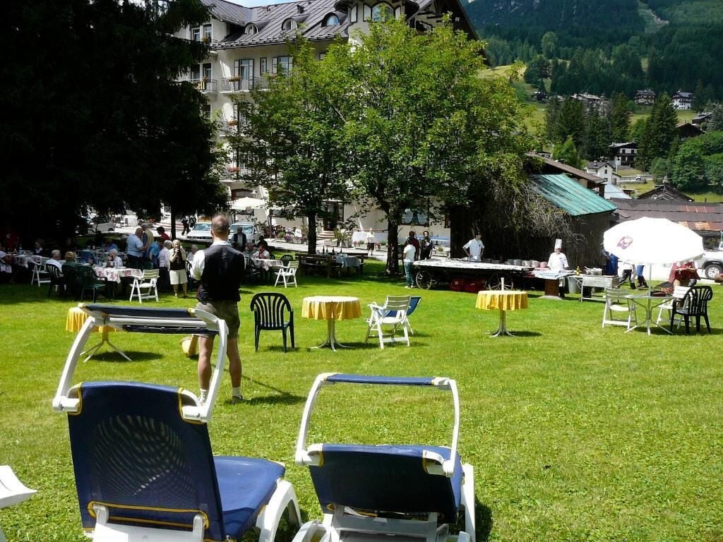 An outdoor seating area with lawn chairs and tables, surrounded by trees and buildings in a mountainous area.