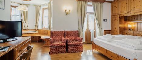 Una habitación acogedora con una cama de madera, un televisor, un sillón rojo estampado y armarios de madera.