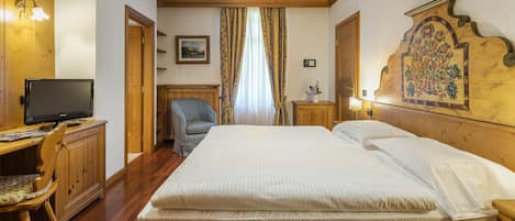 Habitación de hotel con cama, escritorio con computadora, una silla y cabecera de madera con diseño floral.