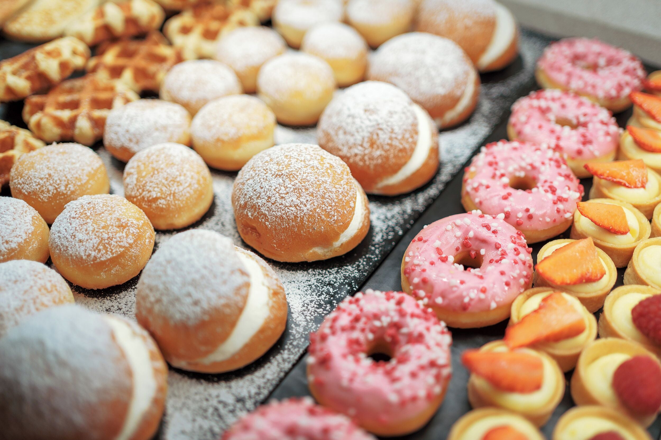 Diversa selección de pasteles, incluyendo rosquillas y gofres.